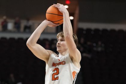 A basketball player holds the ball over his head as he prepares to shoot a basket.